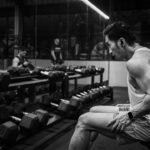 Praticante sentado em banco de academia durante intervalo entre exercícios