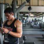 Profissional de educação física usando o celular em uma academia, representando gestão da presença digital no Google