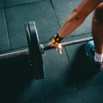 Pessoa segurando barra durante exercício de força em academia
