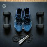 Tênis esportivos ao lado de halteres em ambiente de treino